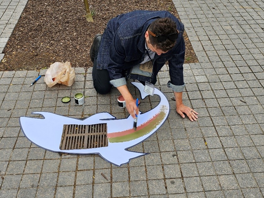 Person painting around a stormwater inlet